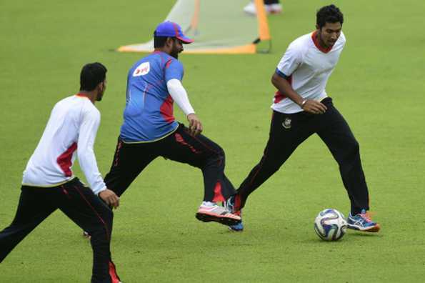 Bangladesh cricketer Soumya Sarkar (R) plays football with teammate Tamim Iqbal (C) during a practice session.