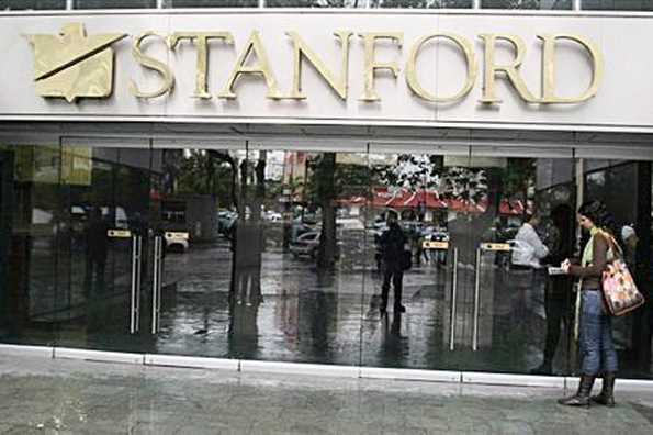 A journalist stands by the main entrance to the headquarters of the Standford Bank in Caracas. Texas financier Allen Stanford, accused of a multibillion dollar fraud that prompted governments to shut down his banks and seize their assets, was located Thursday in Virginia, the FBI said.